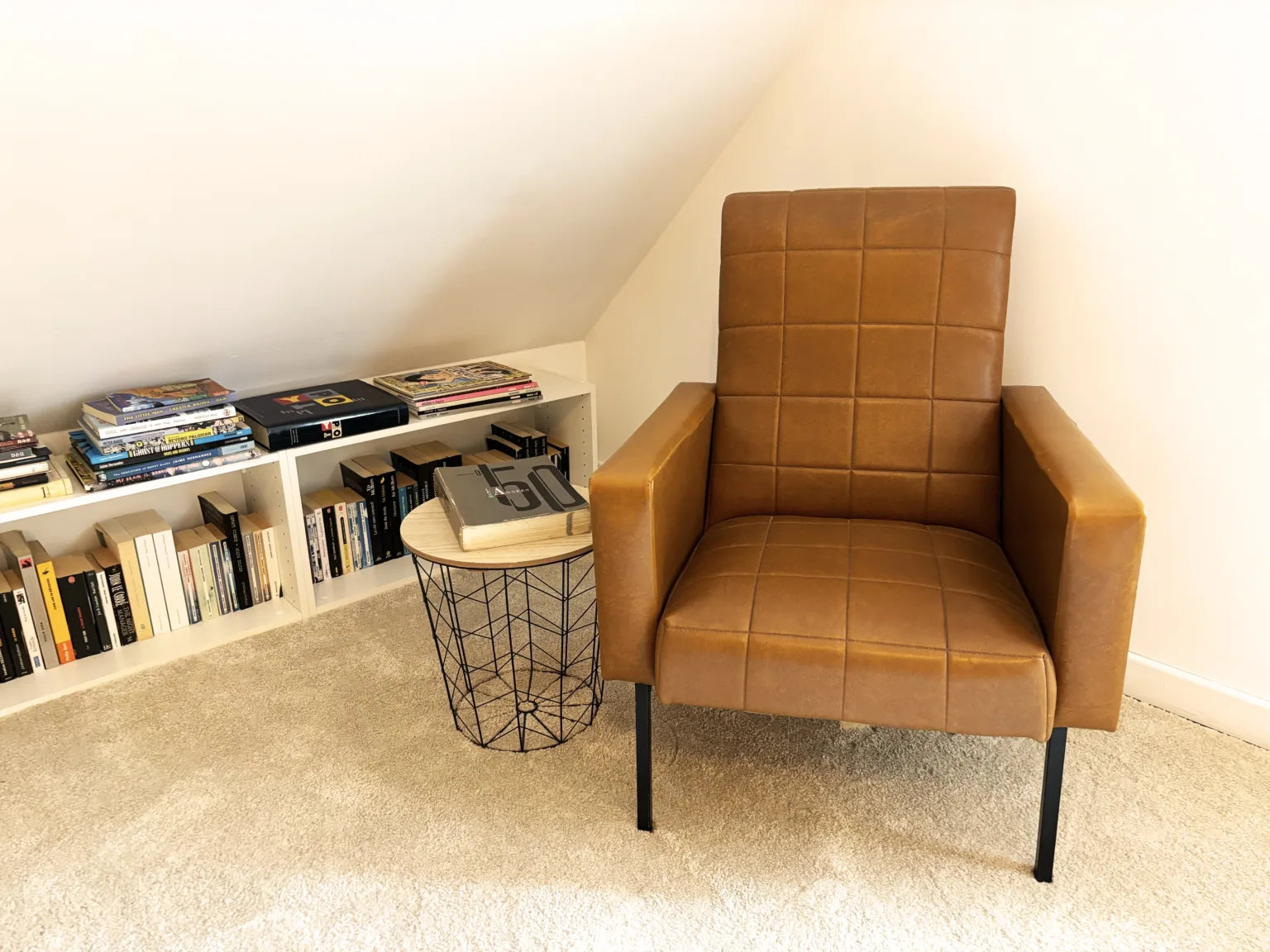 Fauteuil en cuir camel, table d’appoint et livres